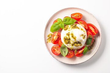 Burrata cheese caprese salad with cherry tomatoes, olive oil, pesto and seasoning. Fresh food concept. 