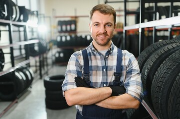 Portrait of smiling warehouse worker standing by the pile of new car tires