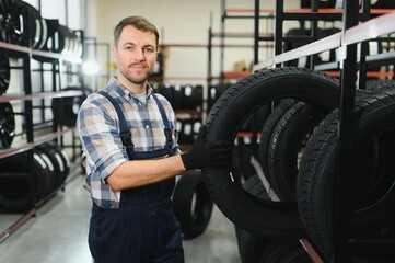 Portrait of smiling warehouse worker standing by the pile of new car tires
