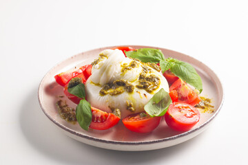 Burrata cheese caprese salad with cherry tomatoes, olive oil, pesto and seasoning. Fresh food concept. 