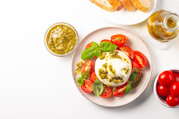 Burrata cheese caprese salad with cherry tomatoes, olive oil, pesto and seasoning. Fresh food concept. 