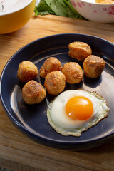 A view of a plate of polenta roasted potatoes and a fried egg.