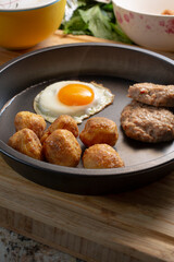 A view of a plate of polenta roasted potatoes and a fried egg.