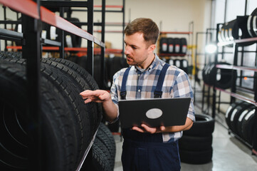 Professional worker with tire. Man is in the tire fitting car service