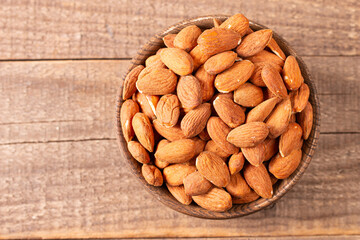 Raw peeled almonds in brown wooden bowl. Organic food concept. 