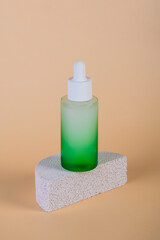Green glass cosmetic bottle, Skin care or sunscreen cosmetic with stylish props on cream background.