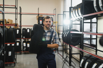 Professional worker with tire. Man is in the tire fitting car service