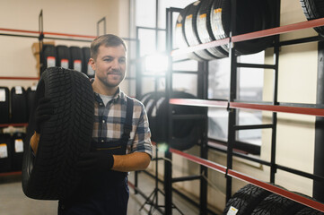 Portrait of smiling warehouse worker standing by the pile of new car tires