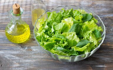 Lettuce and spinach salad with olive oil and vinegar on rustic table, healthy cooking ingredients