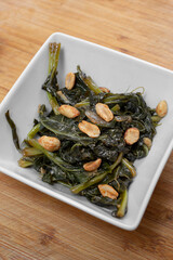 A view of a square bowl of a kohlrabi greens entree.