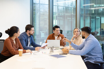 A diverse group of business professionals discussing a project during a meeting in a modern office...