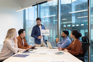 A diverse business team meeting in a modern office setting, discussing financial charts and data...