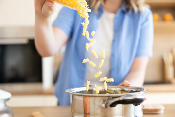 A person is pouring colorful pasta into a pot, symbolizing the joy of cooking in a bright, modern...