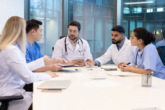 A diverse medical team collaborates in a modern office setting. They are engaged in a discussion.