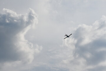 A single-engine airplane soars through a cloudy sky with dramatic lighting and ample space for text placement.