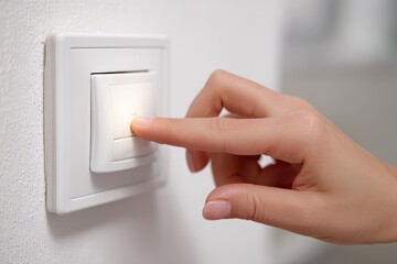 Central European Female Hand Operating a Light Switch - Turning Lights On or Off.