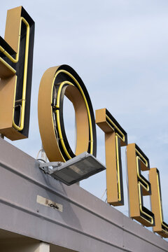 Close-up of large yellow hotel letters on rooftop facade, symbolizing urban accommodation, transient travel stops, and iconic signage as part of visual culture in contemporary travel