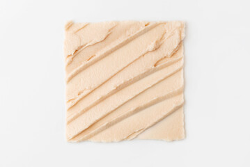 The texture of cosmetic cream in the form of a square on a white background