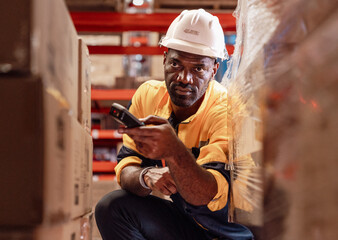 Warehouse manager, store inspector checking stock on storage shelf from inventory checklist. Two diverse ethnic people wear safety hard hat working together examining merchandise at distribution store