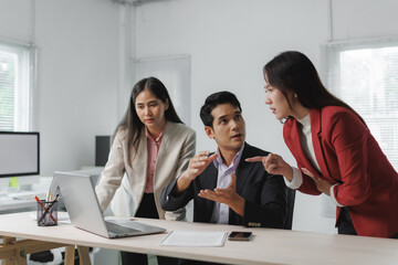 Three business professionals engaging in a serious discussion around a laptop in a modern office,...
