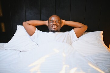 happy african american man waking up in bed