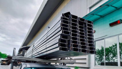 C-channel steel sections stacked in an industrial yard, widely used in construction for lightweight structural framing and roof purlins.