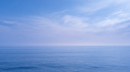 Serene ocean view shows a calm blue sea meeting a light blue cloudy sky.