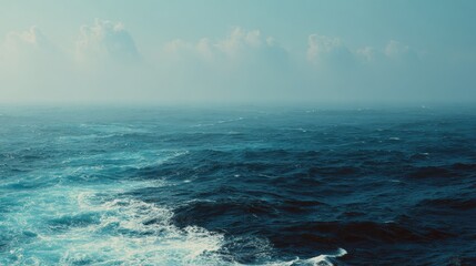 Deep blue ocean waters meet a hazy sky on the horizon at sea