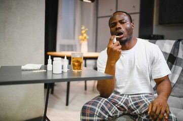 Man experiencing sore throat pain using throat spray for relief on couch at home