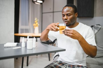 Shot of a young man with a cold recuperating at home. Feeling bad. Sick African-American man...