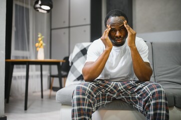 Closeup of young african american man suffering from headache at home, touching his temples....