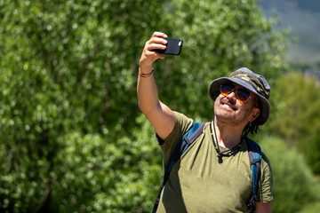
Caucasian man taking a selfie with smartphone while hiking on a sunny summer day