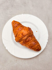 Delicious golden brown croissant resting on white plate