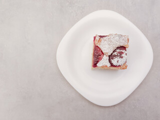 Delicious plum cake on elegant white plate copy space