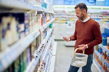 Man Shopping in Pharmacy Holding Product and Basket While Choosing Items