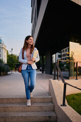 Young Professional Woman Walking Outside an Office Building During Golden Hour