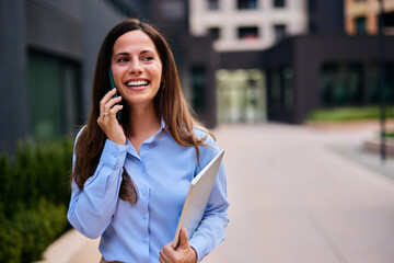Professional Woman Talking on Phone and Smiling Outdoors in Business Setting