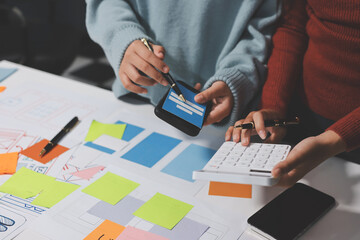 UX UI designer testing prototype on a phone, discussing and brainstorming on wireframes for a...