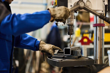 Worker Operating Drill Press on Metal Component in Industrial Workshop