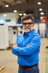 Confident Professional Man in Industrial Setting Wearing Blue Shirt and Glasses
