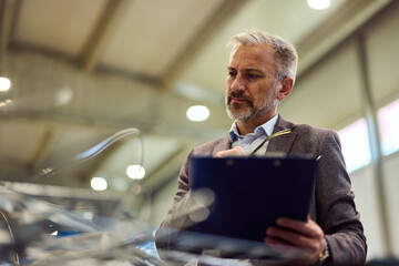 Focused Engineering Manager Reviewing Notes in a Modern Industrial Facility