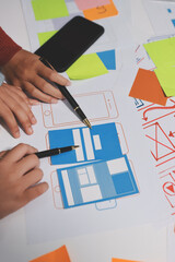 UX UI designer testing prototype on a phone, discussing and brainstorming on wireframes for a...