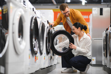 Couple choosing wasing machine at electronics store
