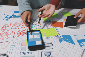 UX UI designer testing prototype on a phone, discussing and brainstorming on wireframes for a...