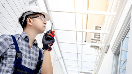 Asian man engineer headshot using walkie talkie to cooperate with the worker team while looking at...