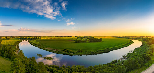 Aerial view of beautiful sunset in countryside with river and grain fields