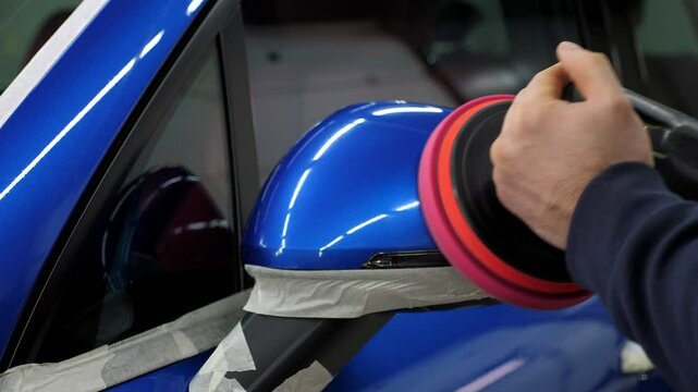 Close-up of a car polishing in a modern car dealership. Car care. A locksmith polishes the car with wax.