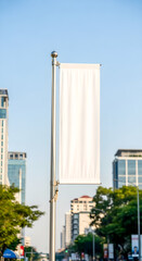 Blank white banner on a city street provides space for advertising or a message with a clear, bright sky as background