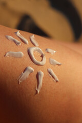 Sunscreen on a woman's leg. Sun design made of sunscreen on skin close-up. Summer season, beach, sunbathing. Woman sunbathing on the beach. Cream protects skin from sunburn, safe tanning, protection