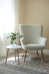 Comfortable armchair and table with vase of flowers near window indoors. Interior design